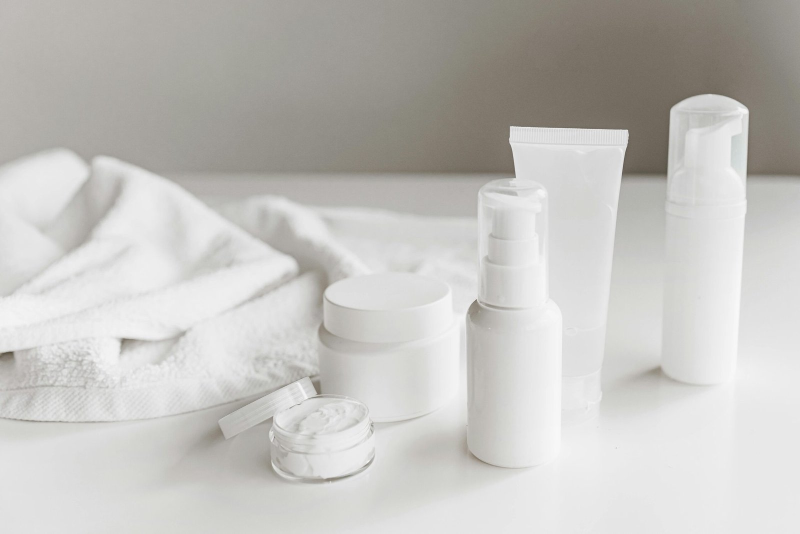 Clean and stylish display of skincare products on a white surface with a towel backdrop.